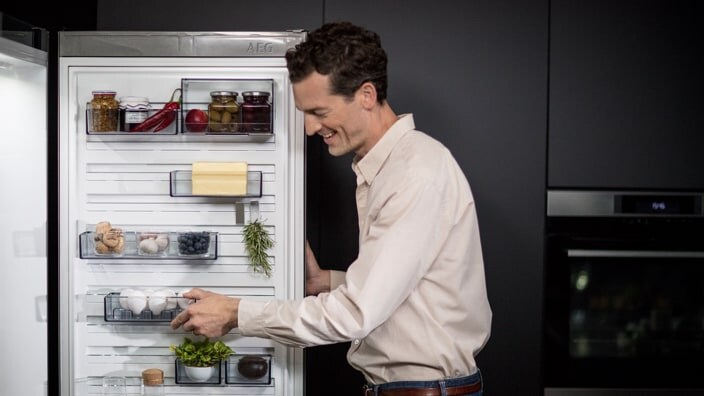 Mies avaa jääkaapin oven