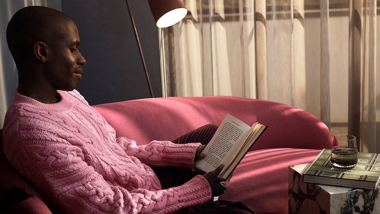 Mies istuu ja lukee sohvalla