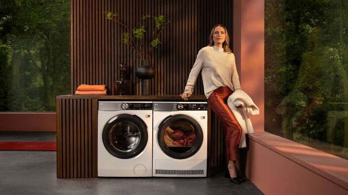 Nainen istuu kuivausrummun päällä ja odottaa kuivausohjelman loppumista. 