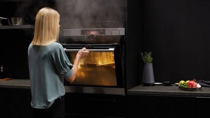 Nainen on laittamassa ruokaa höyryuuniin.