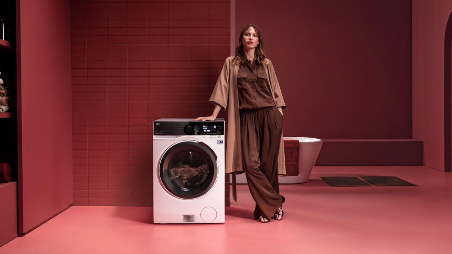 Vapaasti sijoitettava kuivaava pesukone henkilön vieressä punaisessa huoneessa.
