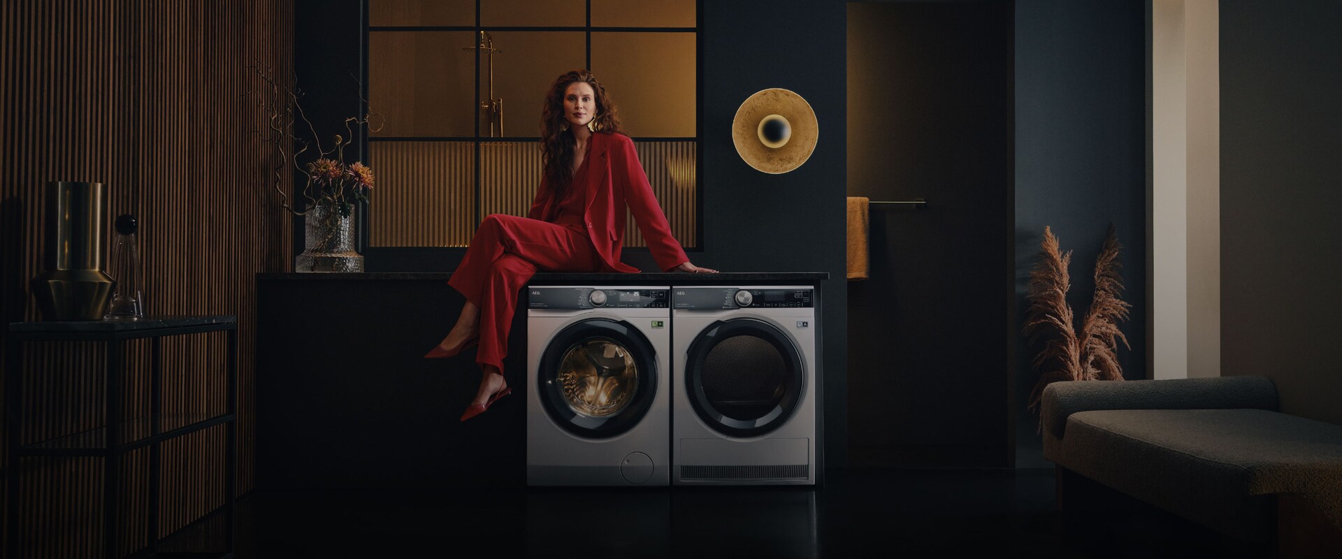 Nainen istuu pyykinpesukoneen päällä.